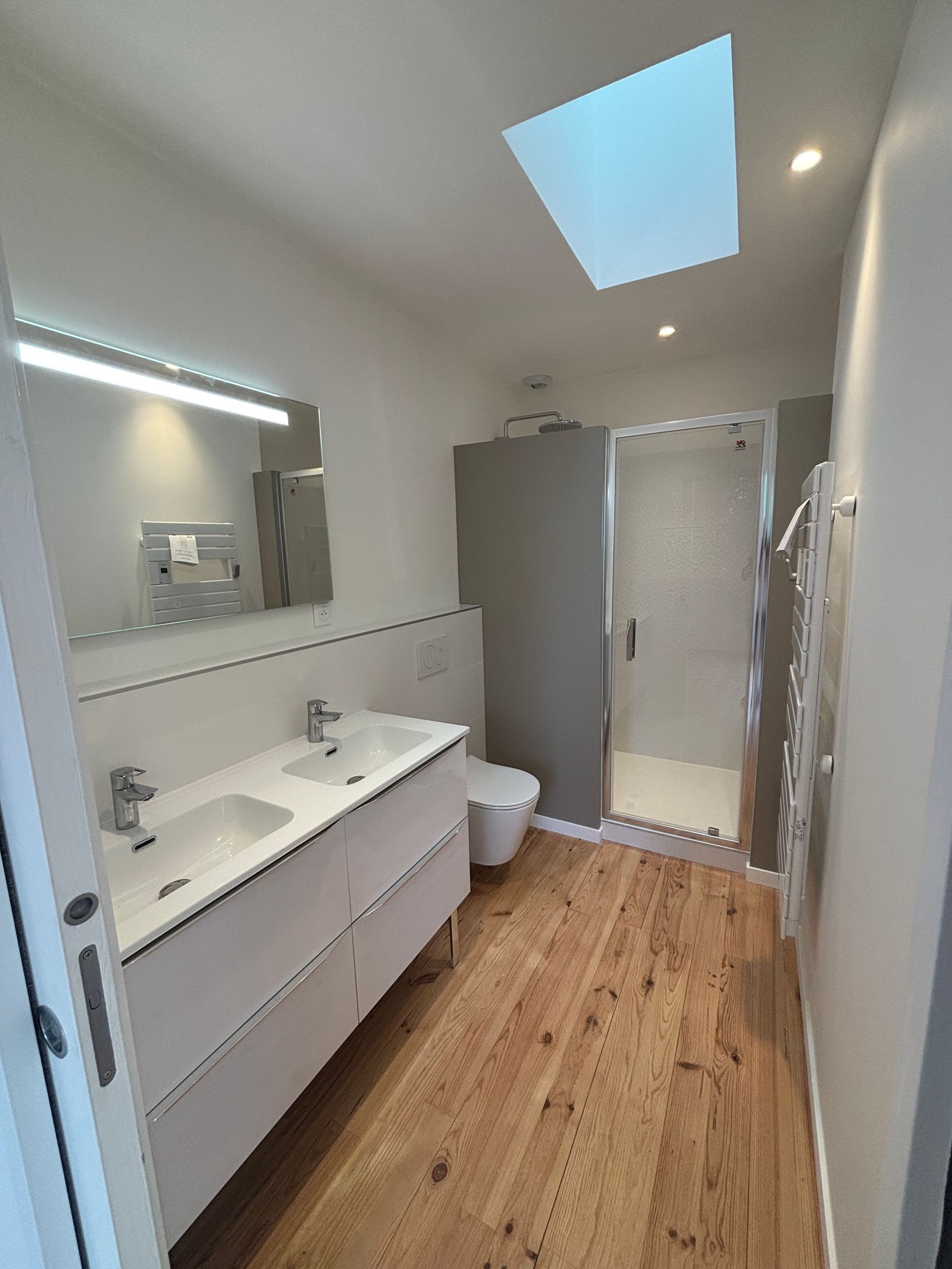 Une salle de bain moderne avec douche à l'italienne, sol en mosaïque, murs en marbre blanc et parois de verre à cadre noir.