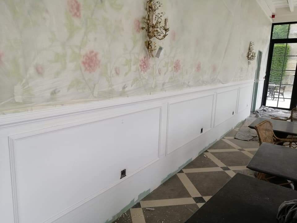 Una habitación con una larga pared blanca y mesas y sillas.