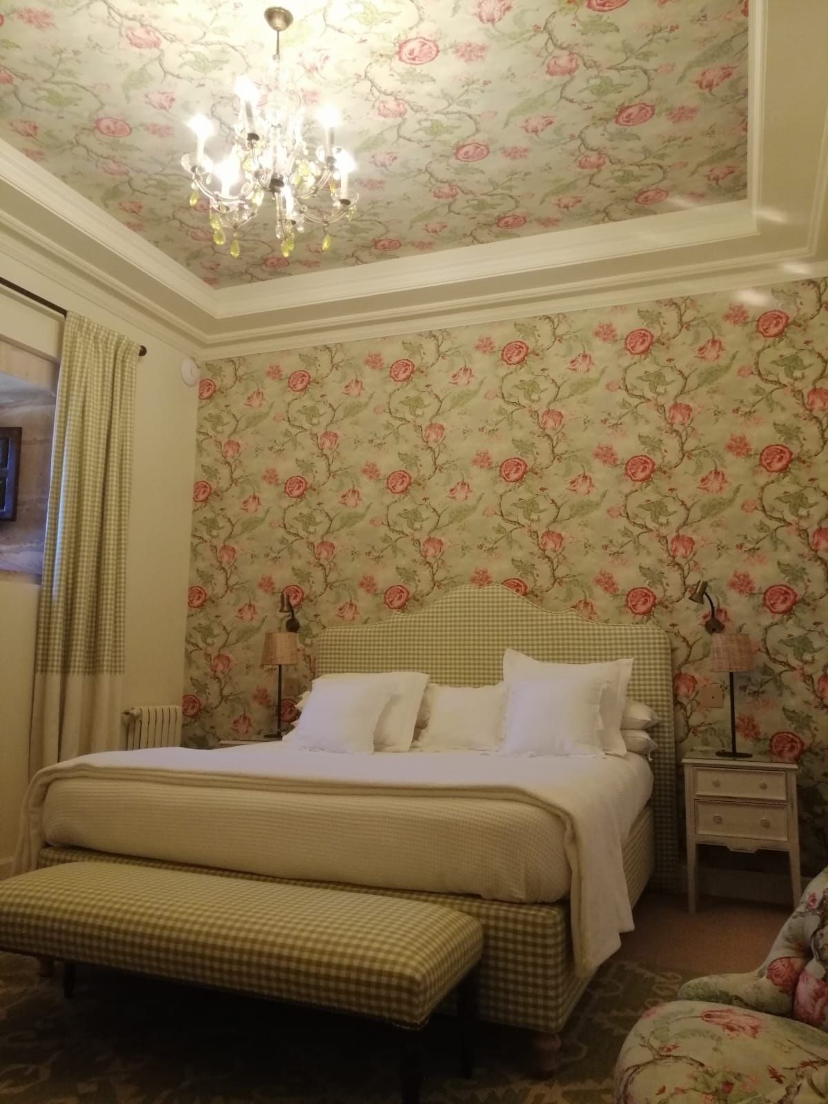 Un dormitorio con una cama, un banco y una lámpara de araña.