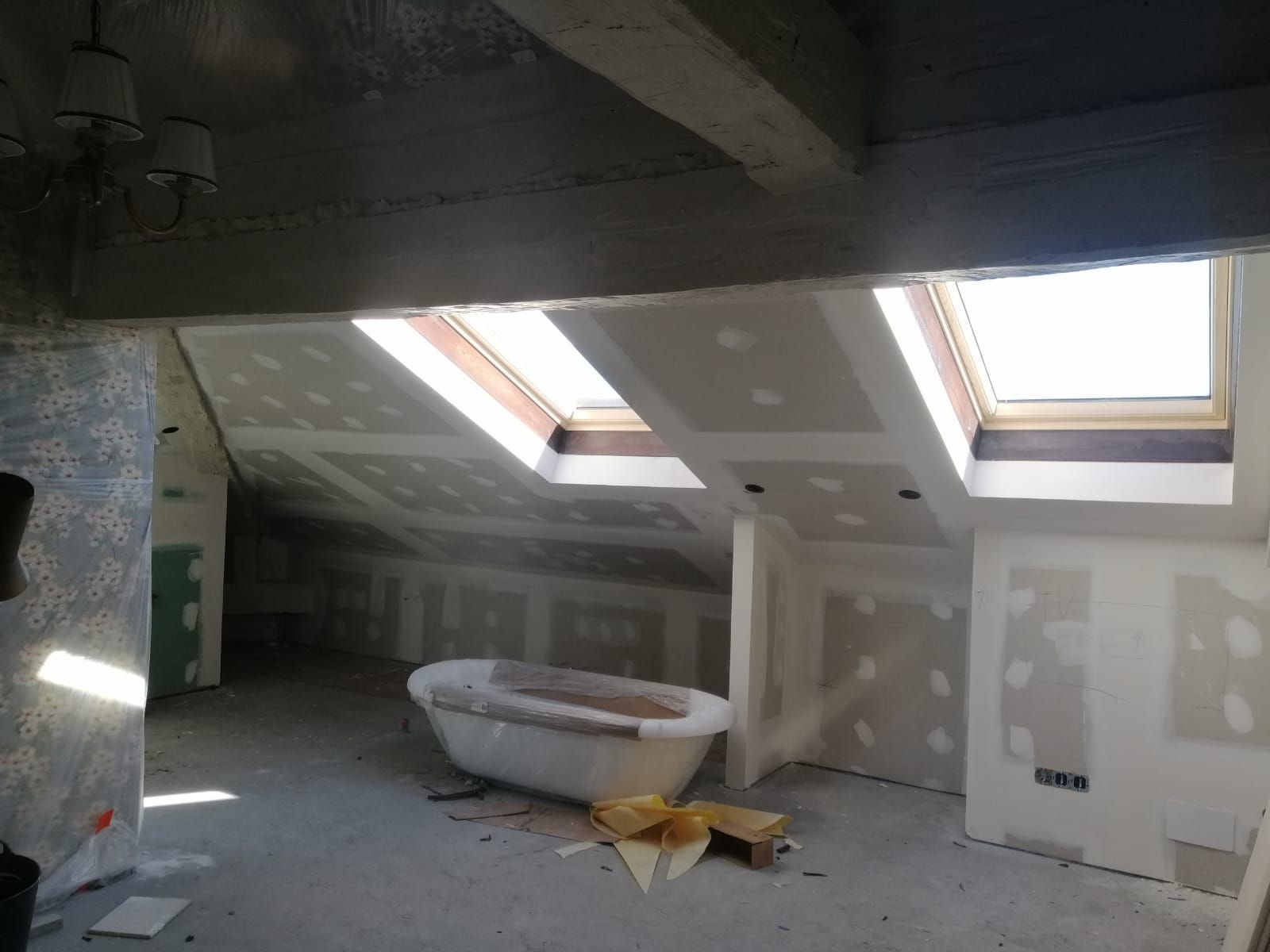 Un ático con bañera y claraboyas en el techo.