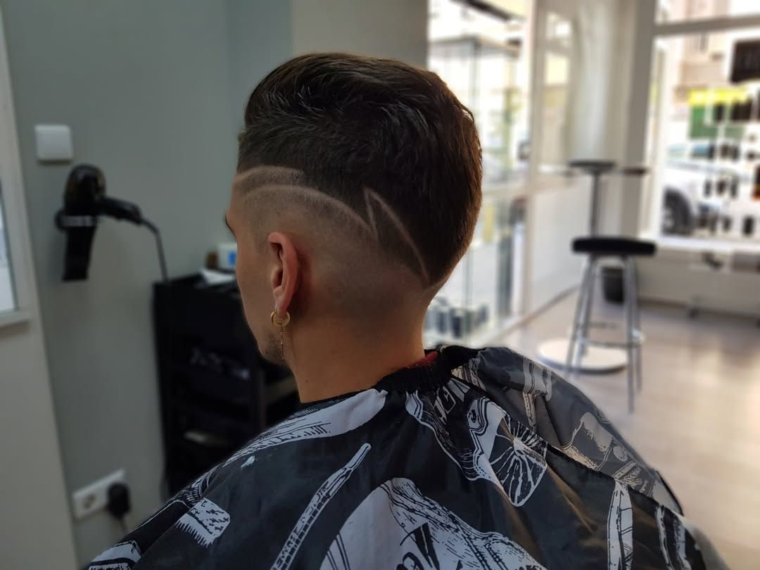 Una persona con capa de barbero luce un corte de pelo corto