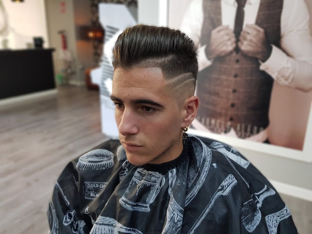 Una persona con un corte de pelo recién hecho, con degradado y un diseño en el cabello