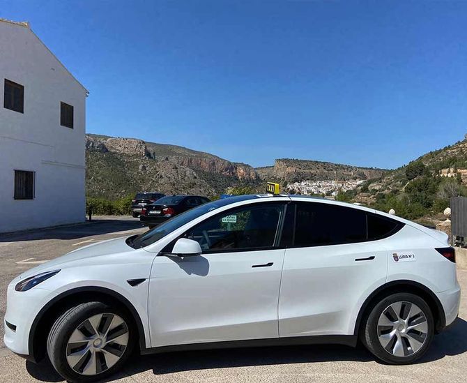 Un Tesla modelo Y blanco está estacionado en un estacionamiento.