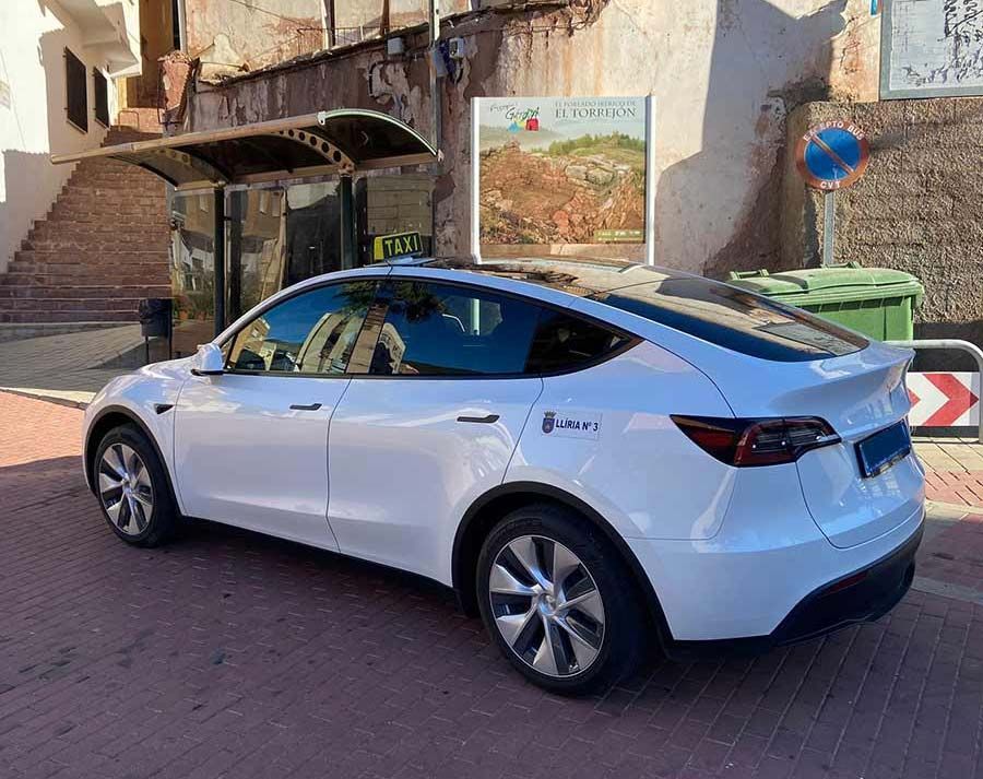 Un Tesla modelo Y blanco está estacionado al costado de la carretera.