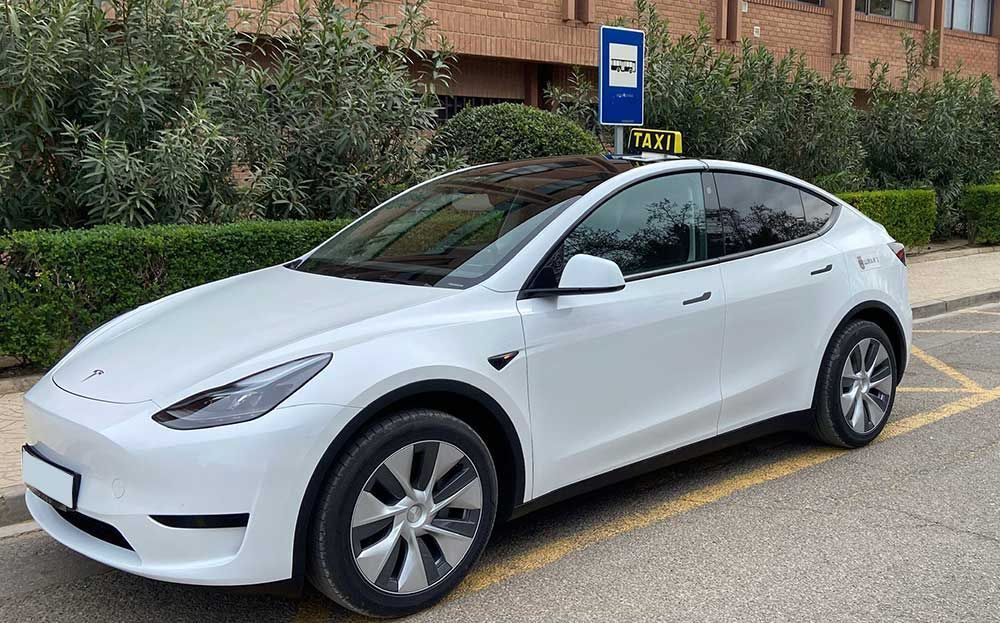 Un Tesla modelo Y blanco está estacionado en un estacionamiento.