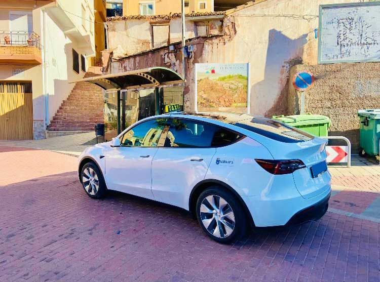 Un Tesla modelo 3 blanco está estacionado al costado de la carretera.