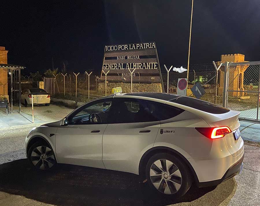 Un Tesla modelo Y blanco está estacionado en un estacionamiento por la noche.