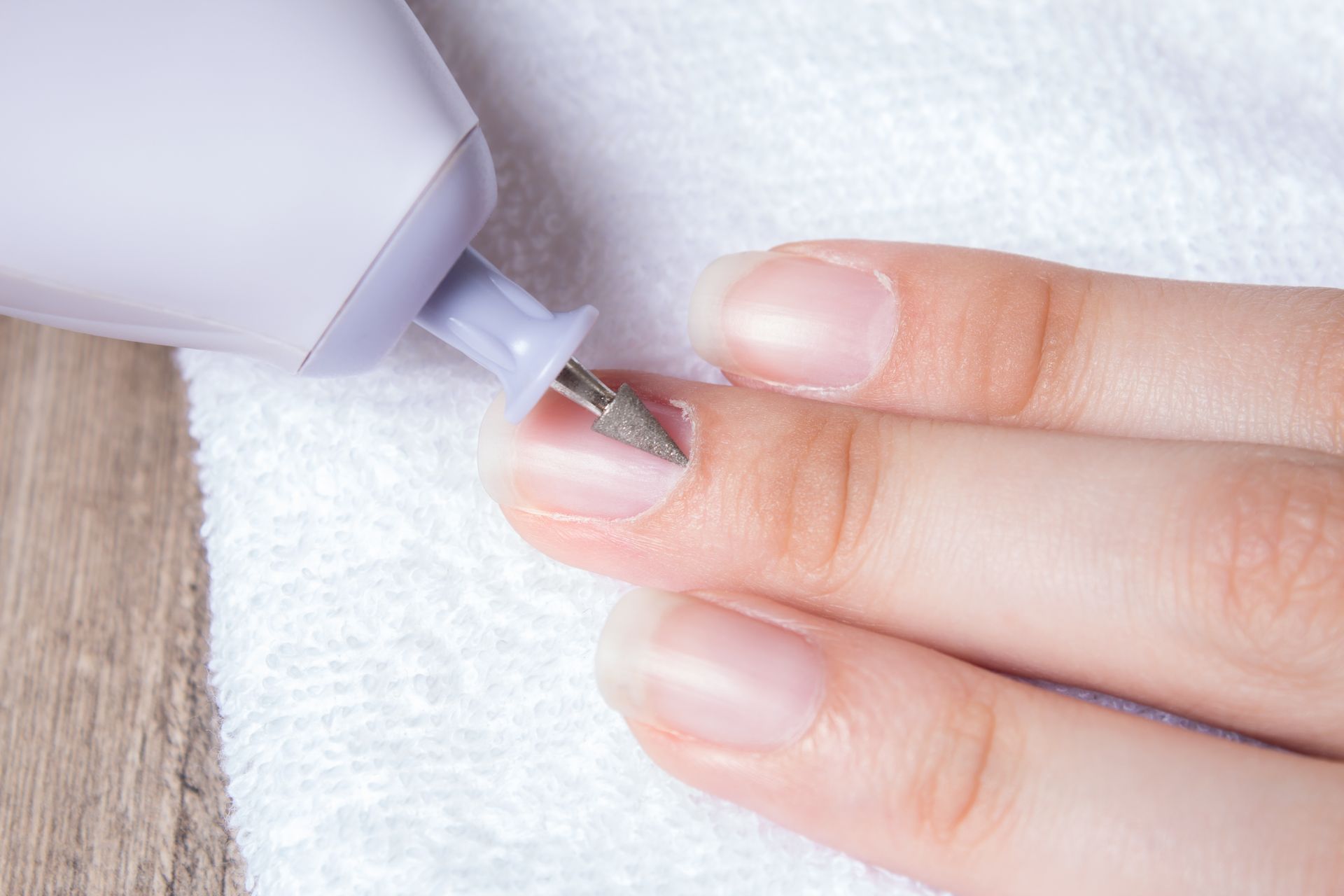 Gros plan d'une main utilisant une ponceuse à ongles.