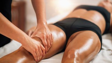 Personne recevant un massage du cuir chevelu ; mains massant la tête. Cheveux bruns, fond neutre.