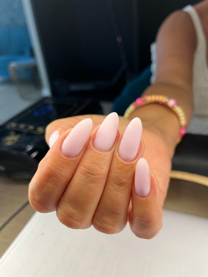 Ongles courts, rose clair, avec des motifs blancs incurvés.