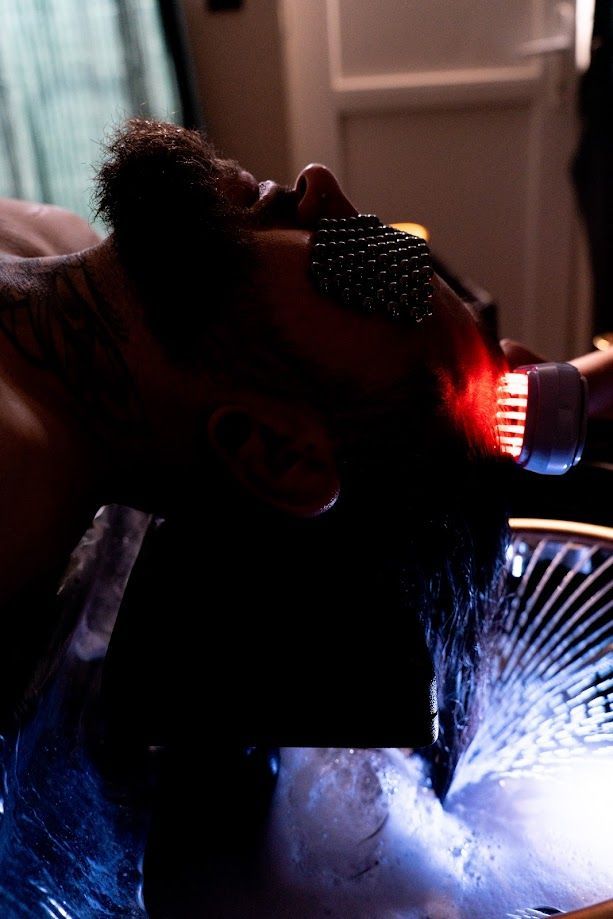 Personne avec une serviette noire sur les yeux recevant un soin de la tête.