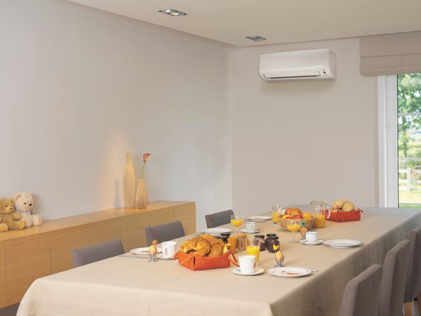 Salle de conférence avec une longue table dressée avec des en-cas et des boissons, des chaises grises et un climatiseur mural.