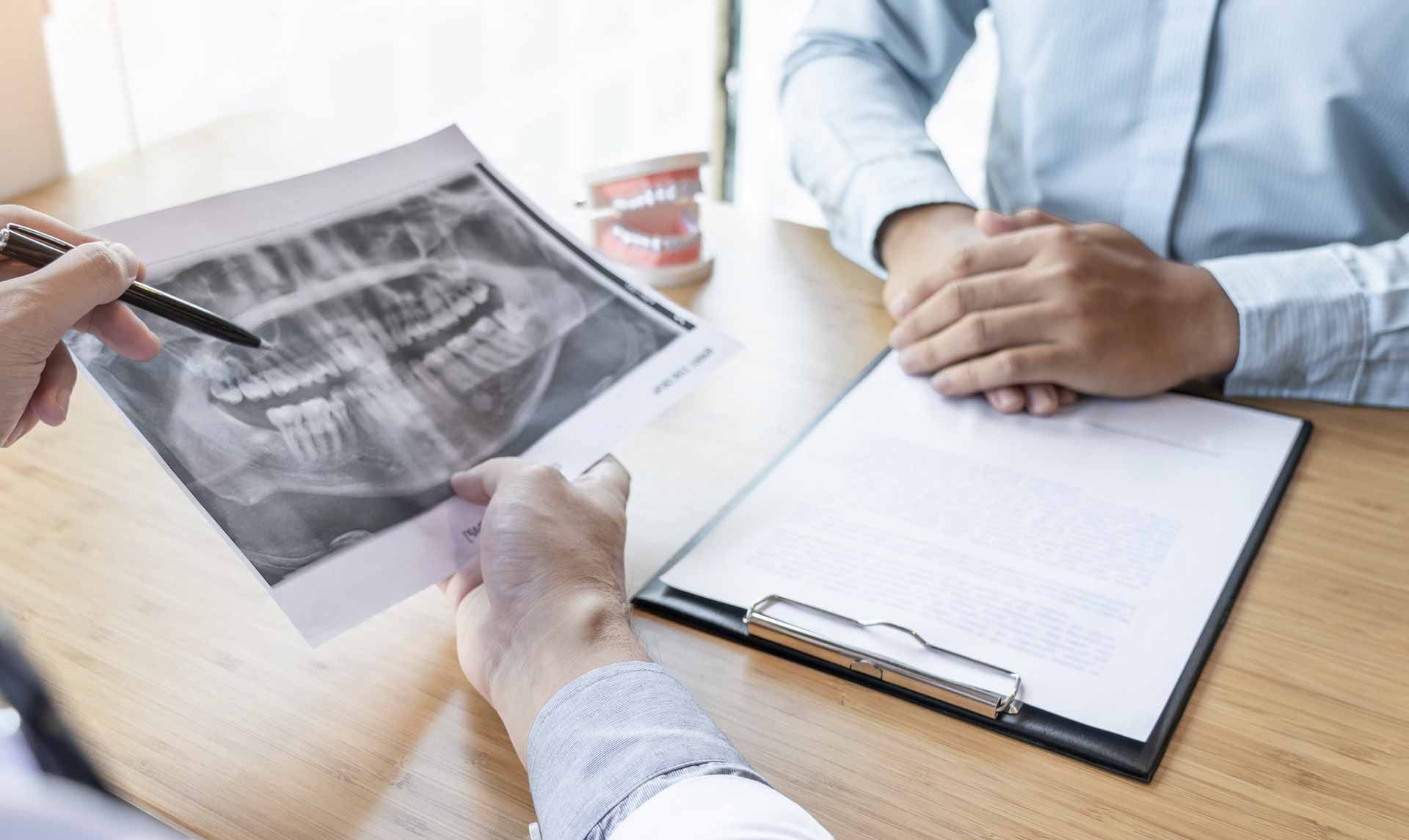 Un dentista está mirando una radiografía de los dientes de un paciente.