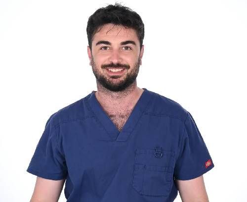 Un hombre con un uniforme azul sonríe para la cámara.