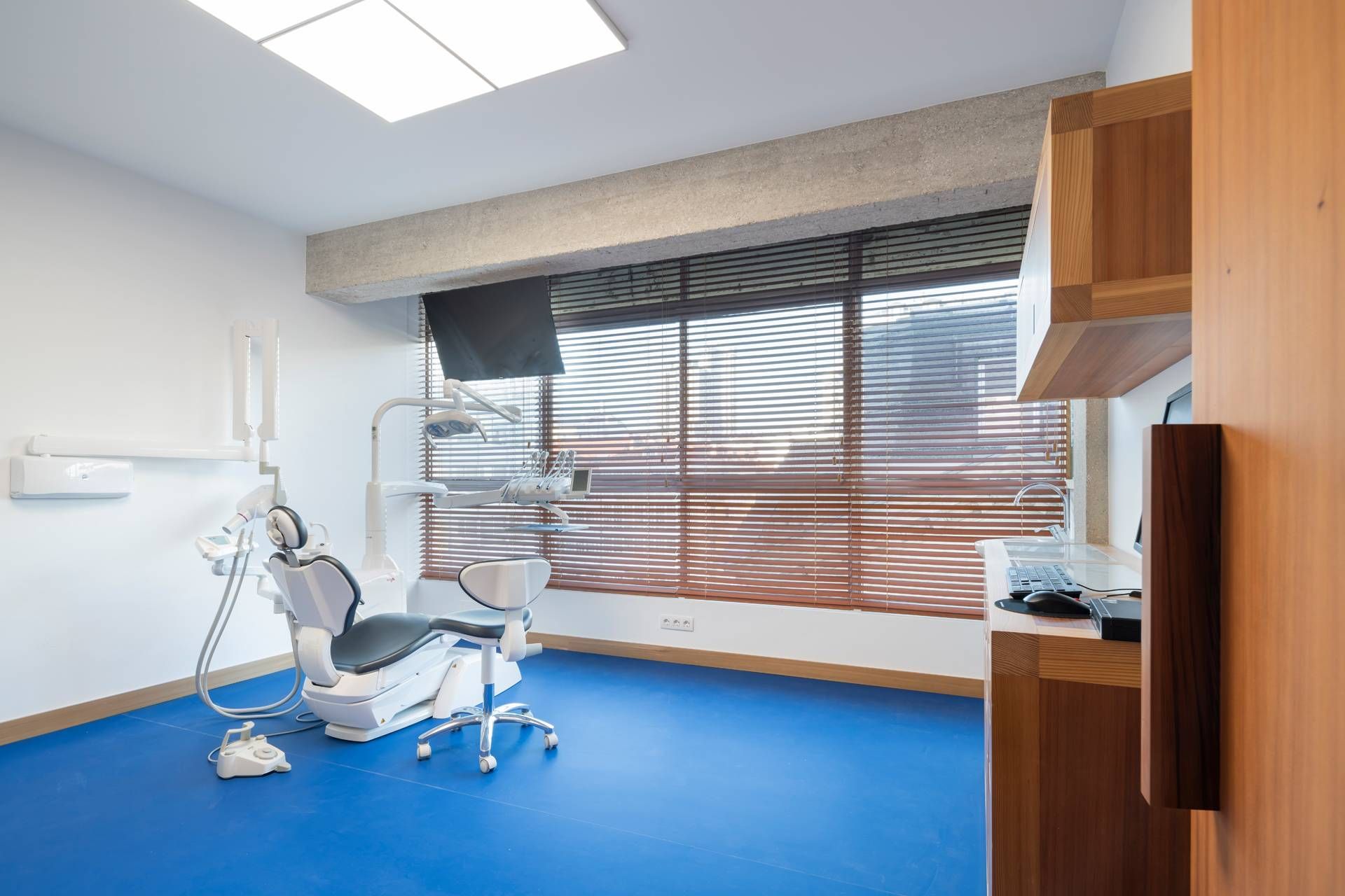 Un consultorio dental con suelo azul y un sillón dental.