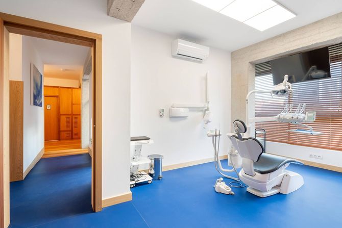Un consultorio dental con sillas azules y un sofá blanco.