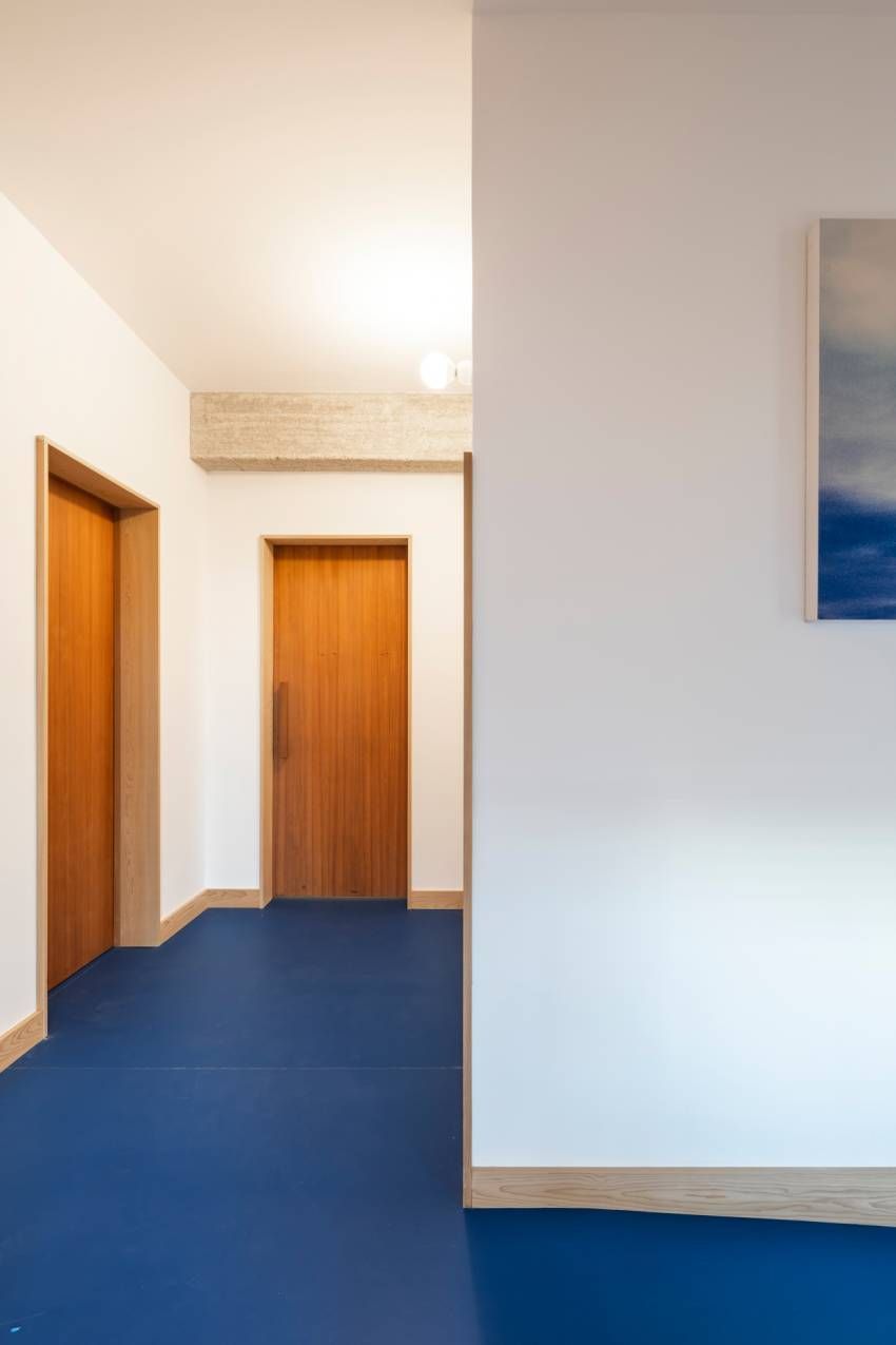 Un pasillo con suelos azules y puertas de madera.