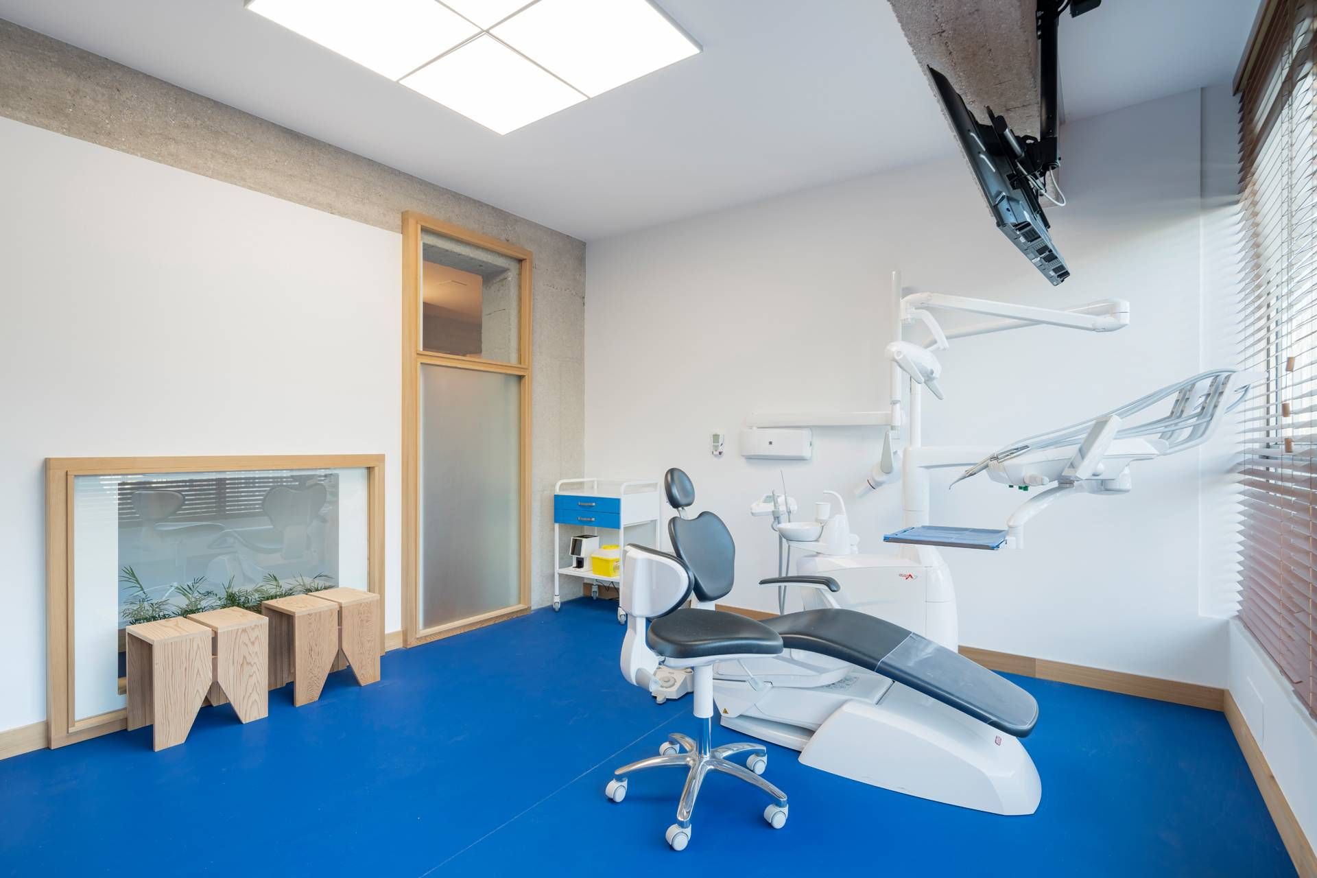 Un consultorio dental con suelo azul y un sillón dental.