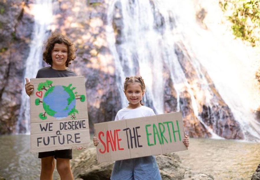Dos niños sostienen carteles frente a una cascada, abogando por la protección del medio ambiente.