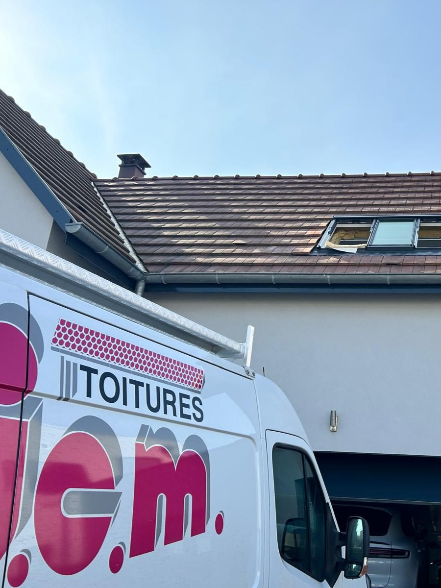 Une camionnette blanche garée près d'une maison au toit de tuiles, par une journée ensoleillée.