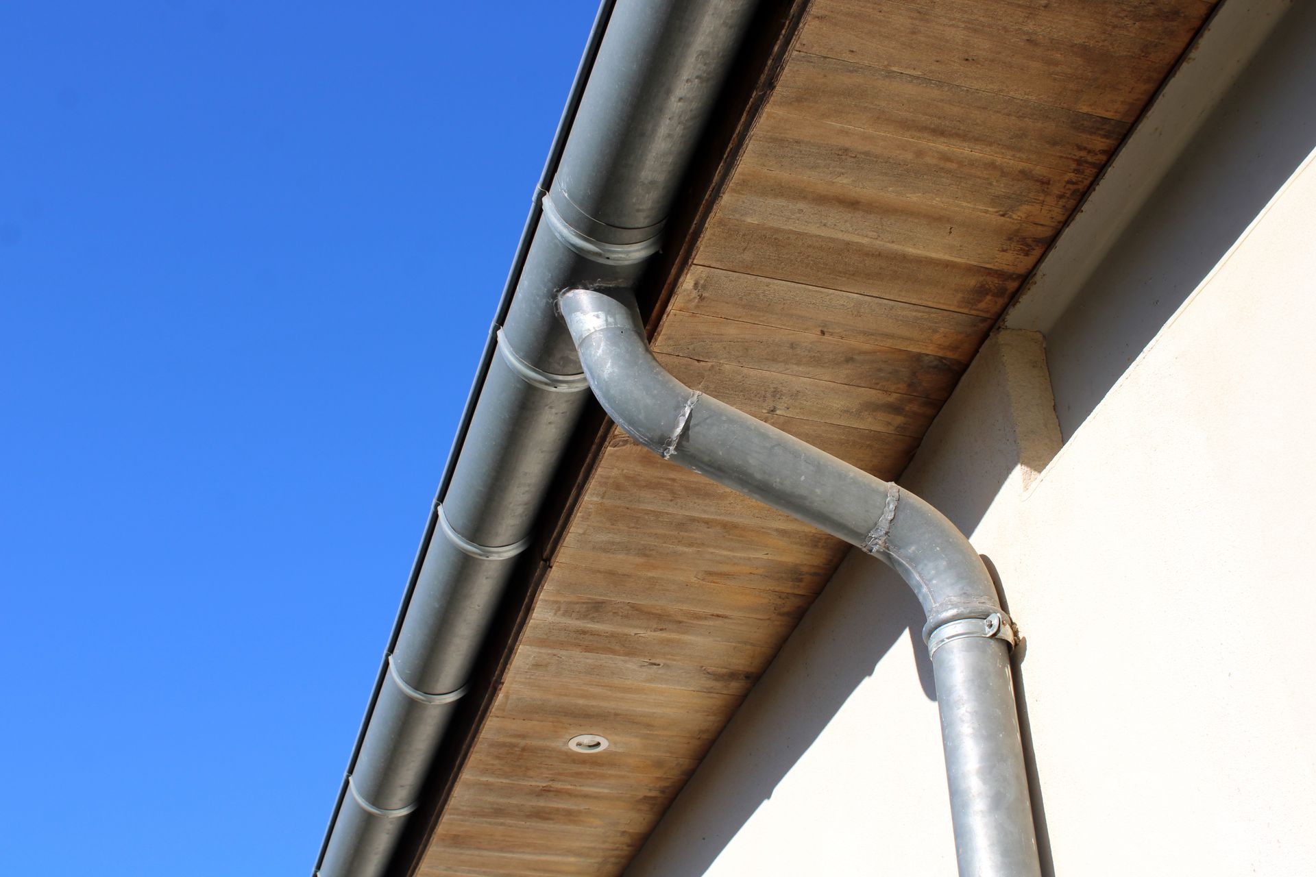 Système de gouttières grises sur un bâtiment avec un ciel bleu en arrière-plan.