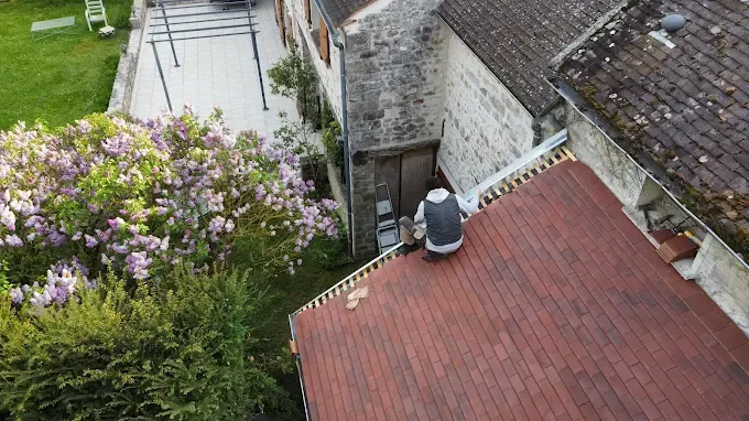 Personne sur le toit rouge d'un bâtiment en pierre.