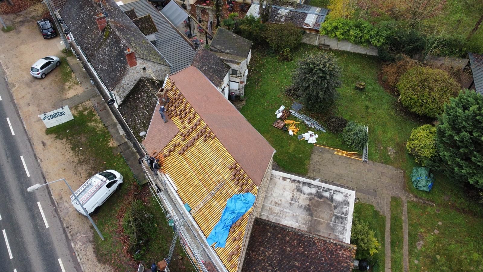 Vue aérienne d'un toit en construction. Des ouvriers travaillent sur le toit avec des matériaux.