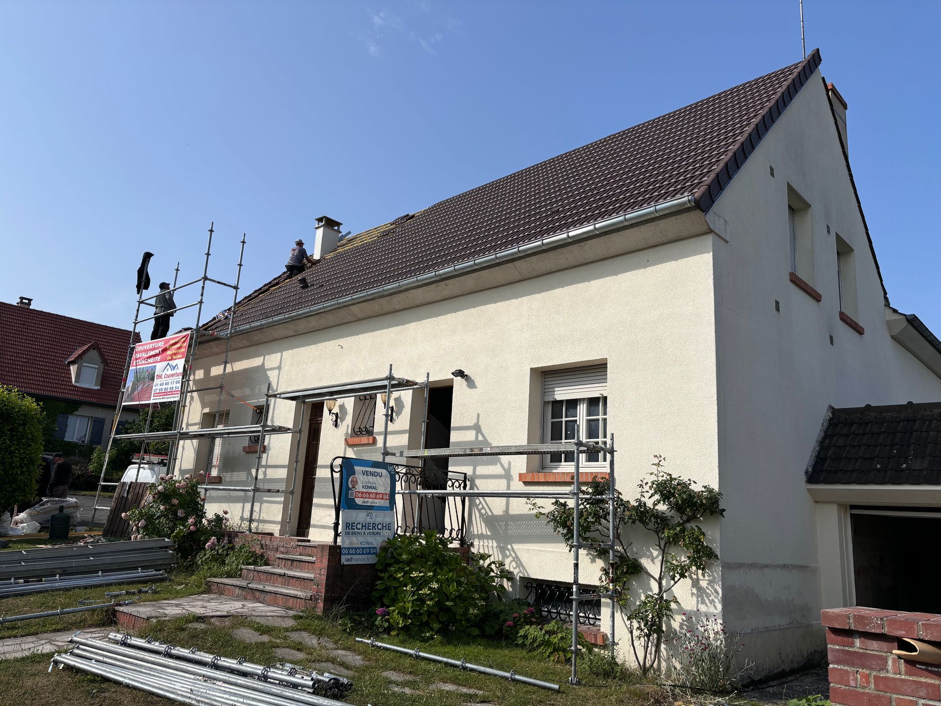 Extérieur de la maison avec échafaudages et travaux de réparation de toiture en cours.