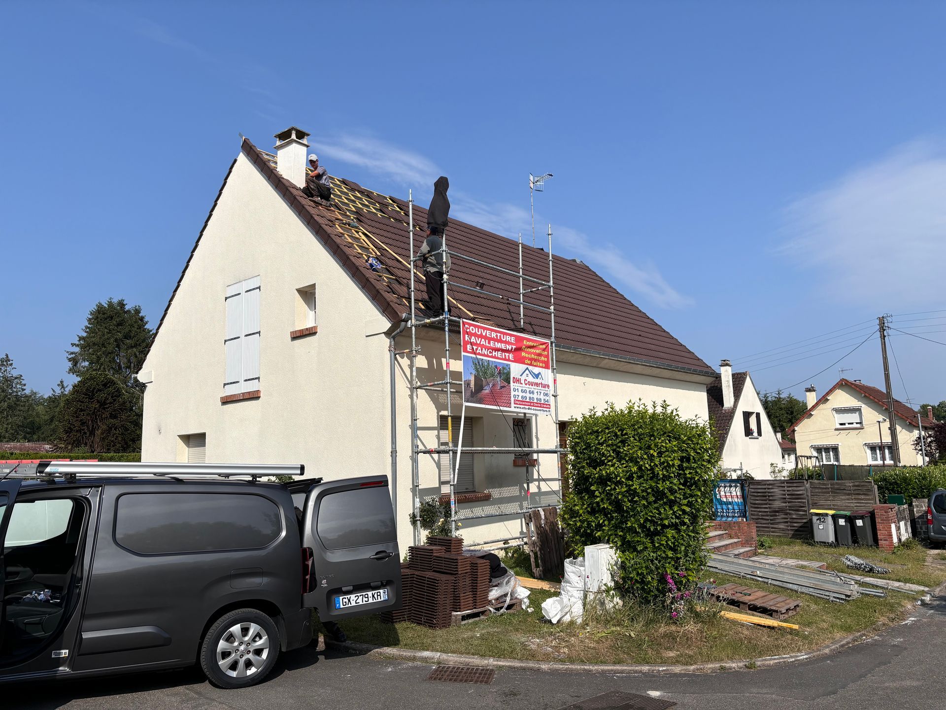 Maison avec des ouvriers réparant le toit, échafaudages, camionnette garée.