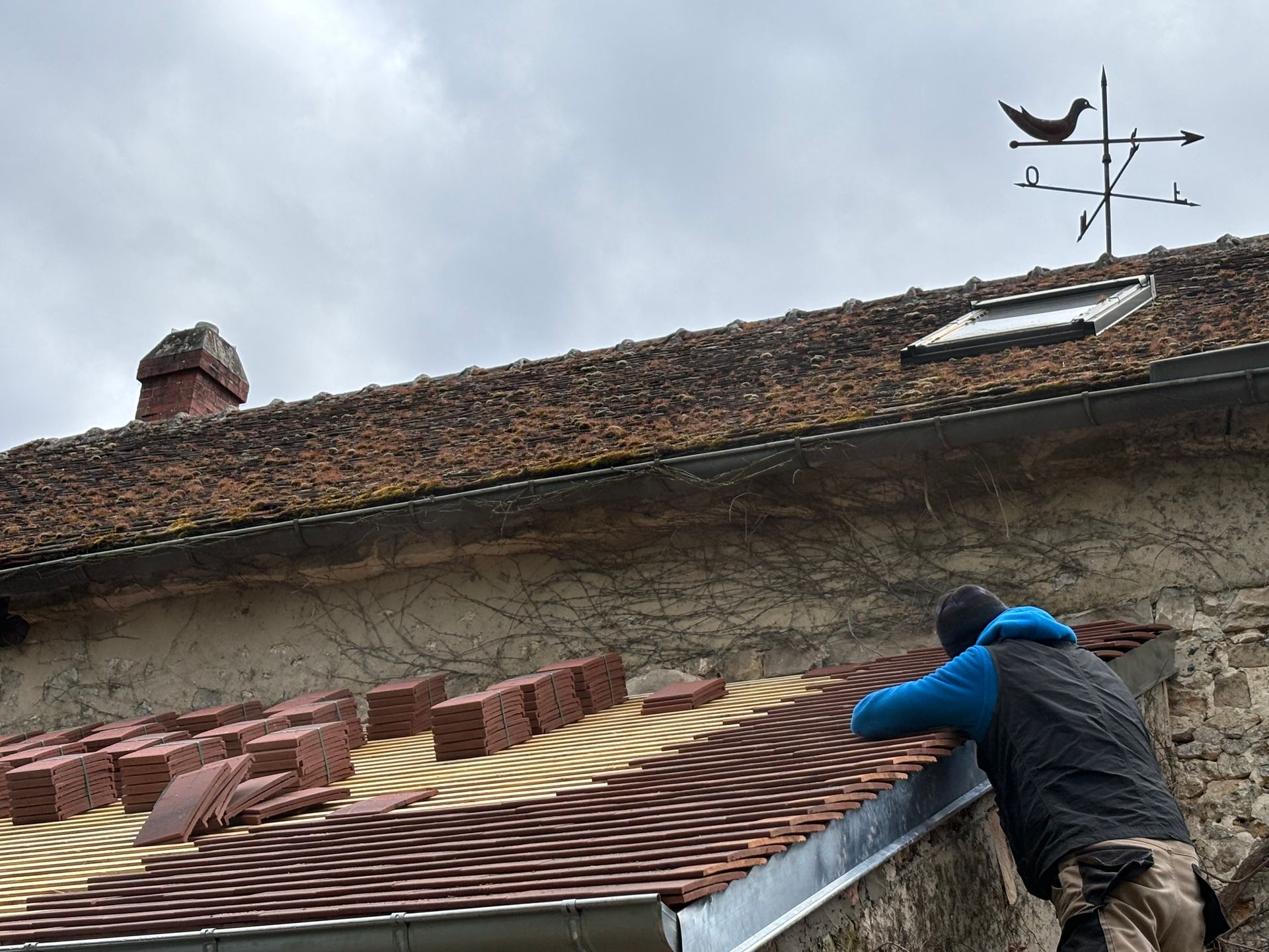 Une personne pose des tuiles sur le toit d'un bâtiment.
