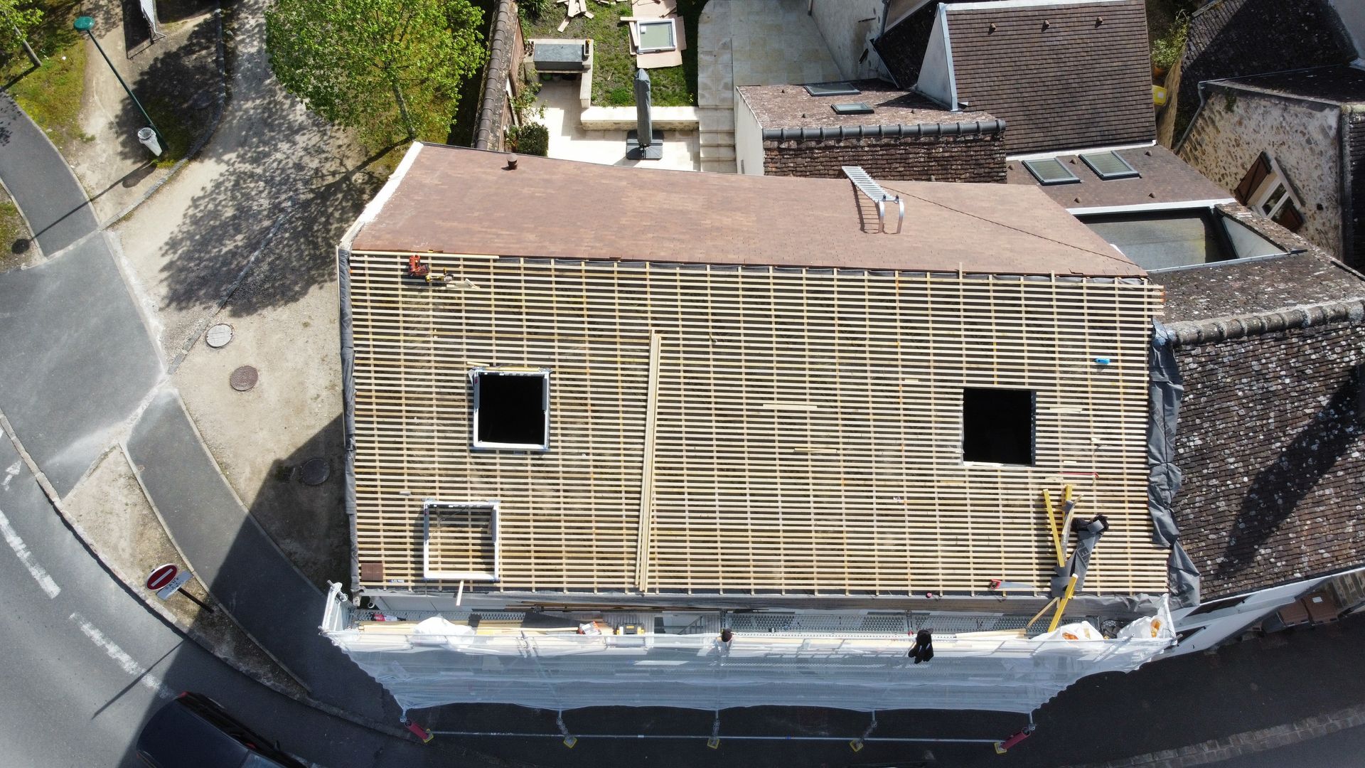 Vue aérienne d'un bâtiment en rénovation, montrant la charpente et la toiture apparentes.