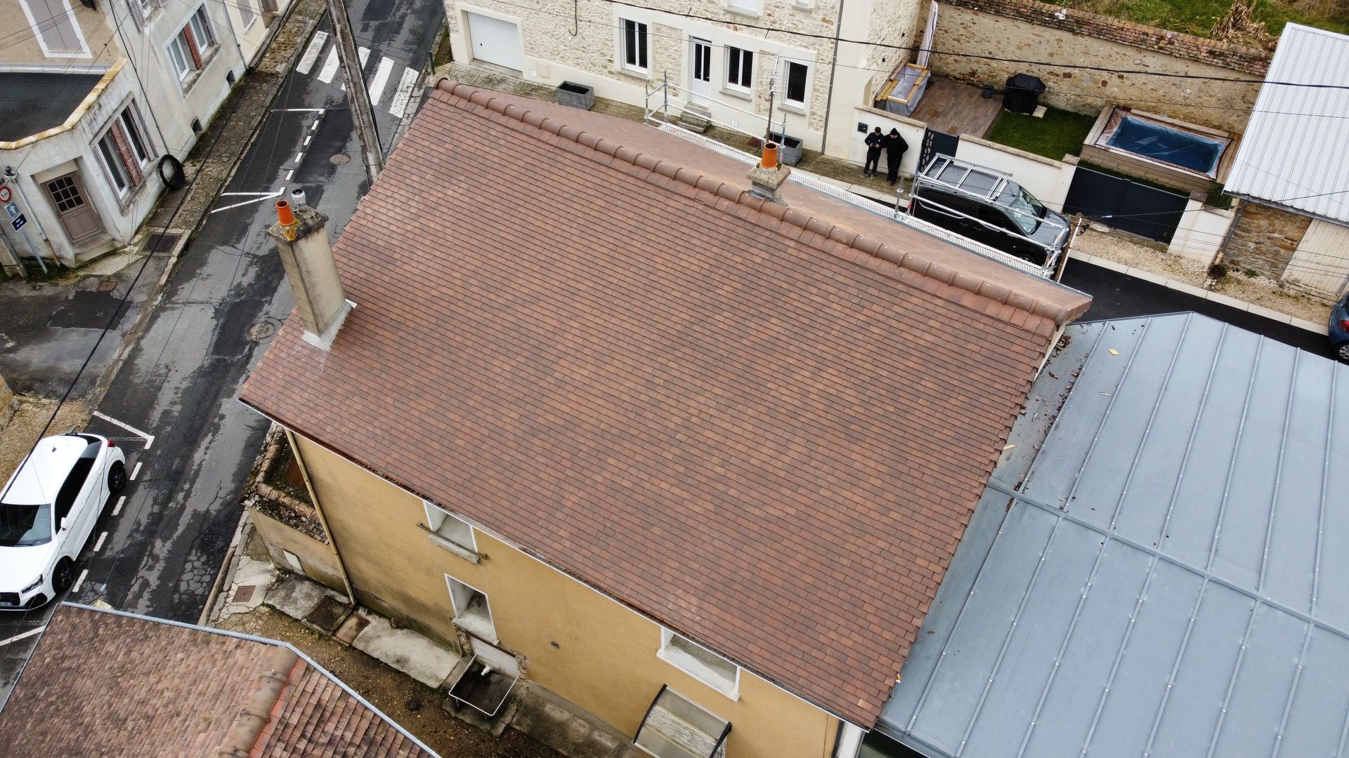 Vue aérienne d'un bâtiment au toit de tuiles brunes en ville.