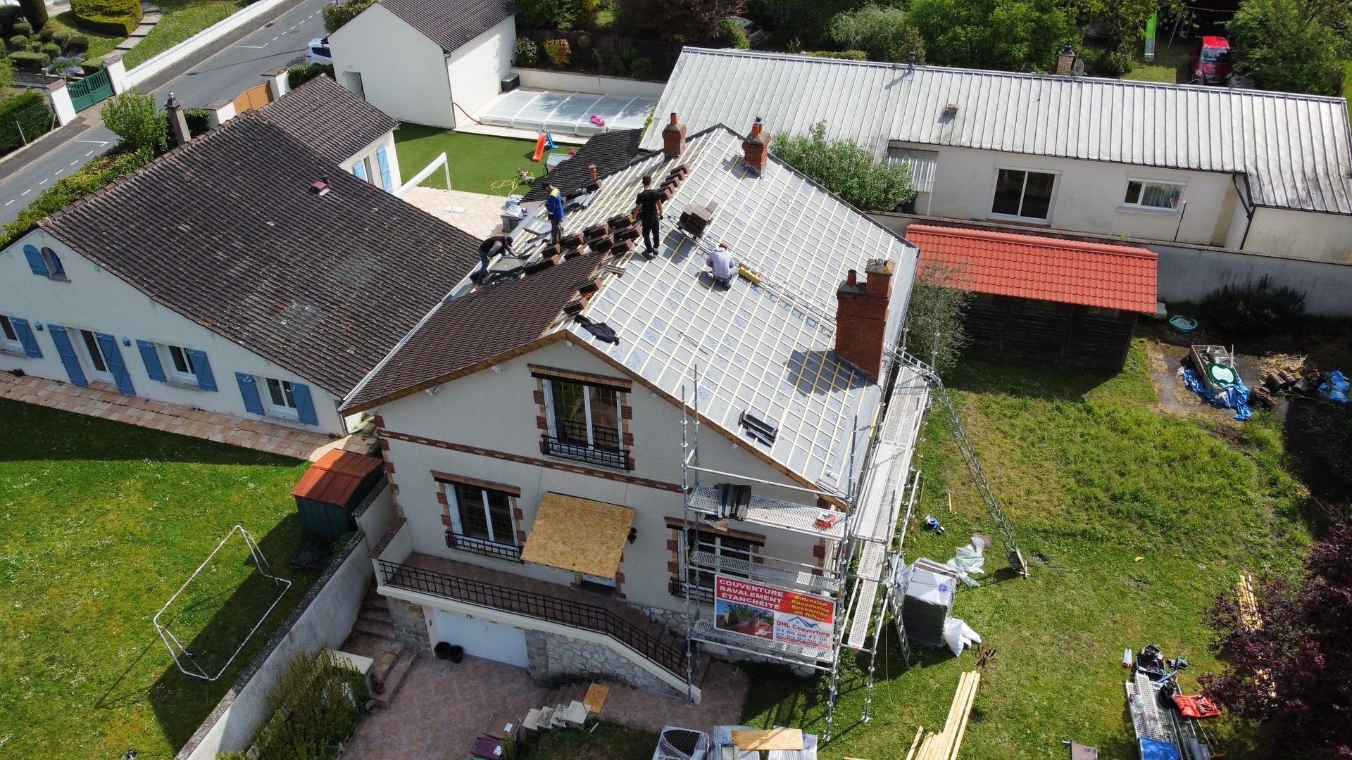 Des couvreurs travaillent sur une maison avec une nouvelle toiture métallique.