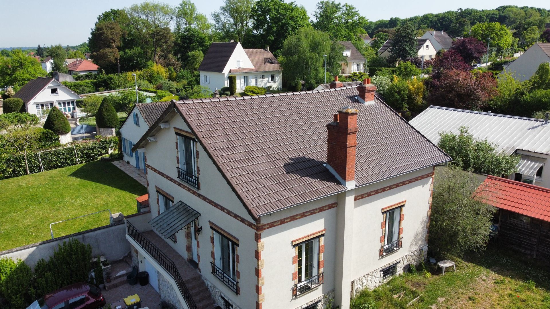 Maison à deux étages avec toit brun et façade en briques rouges.