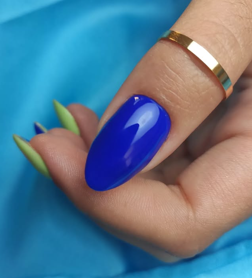 La mano de una mujer con largas uñas azules y un anillo de oro