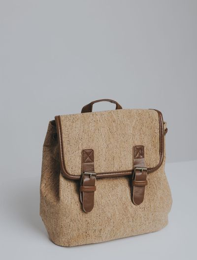 Una fila de bolsos coloridos con asas de cuero están sobre una mesa.