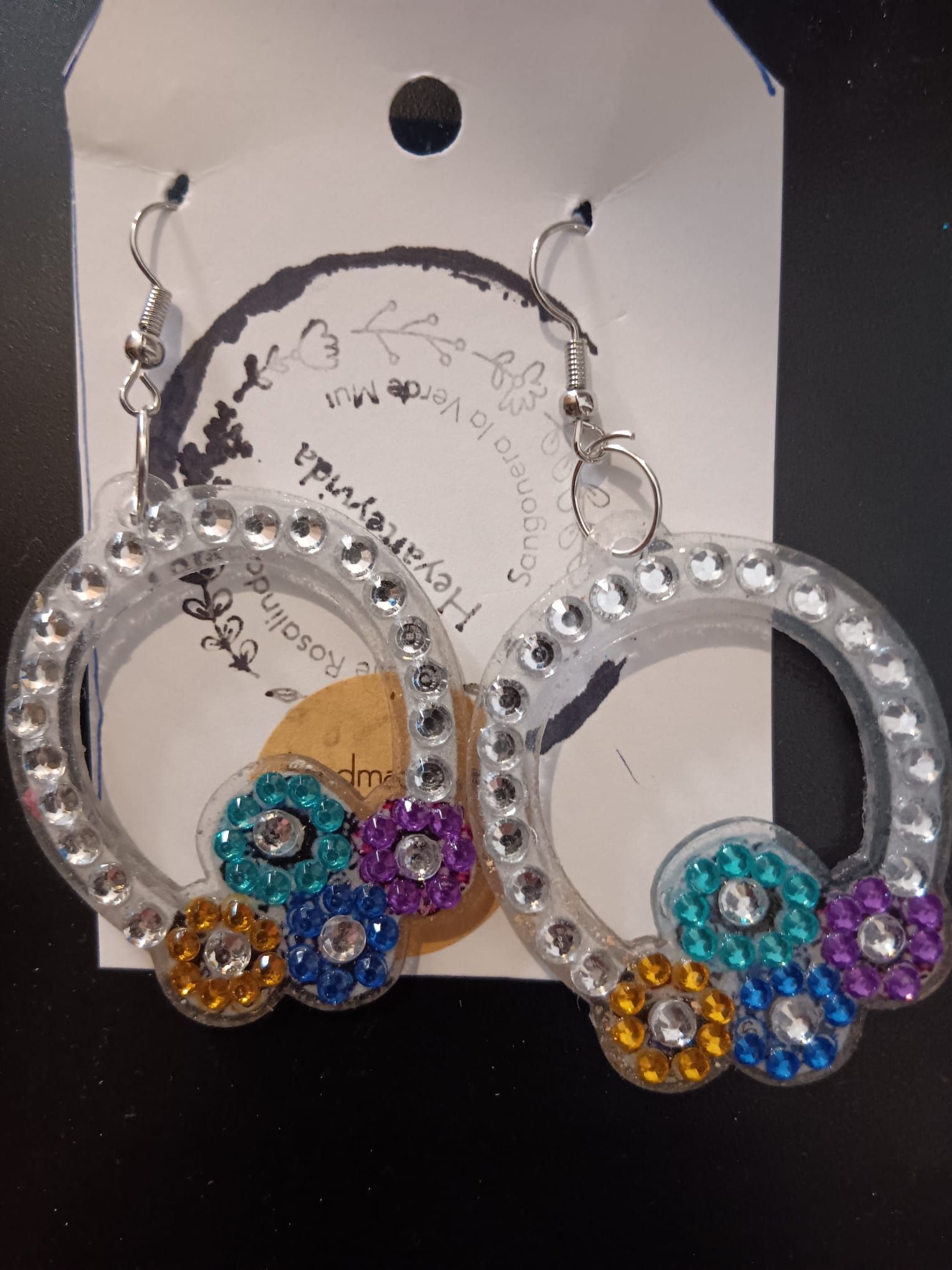 Un par de pendientes transparentes con flores y pedrería.