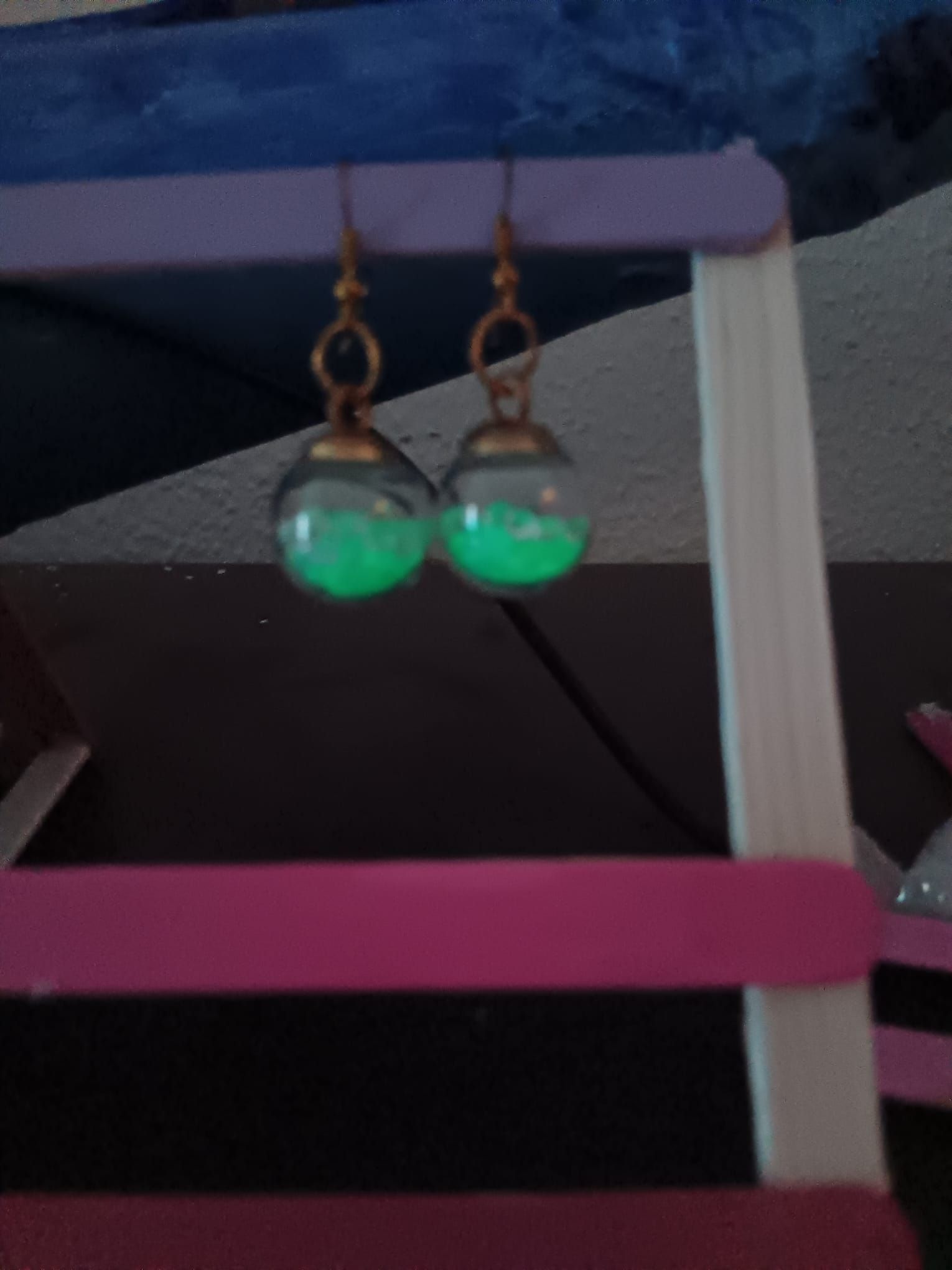 Un par de pendientes que brillan en la oscuridad están colgados en un estante.