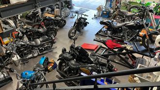 Vue en plongée d'un atelier de réparation de motos avec plusieurs motos à différents stades d'entretien sur le sol