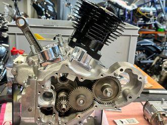 Un moteur de moto partiellement assemblé sur un établi, montrant les engrenages internes, un cylindre métallique