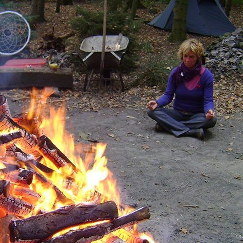 Frau meditiert vor Feuer