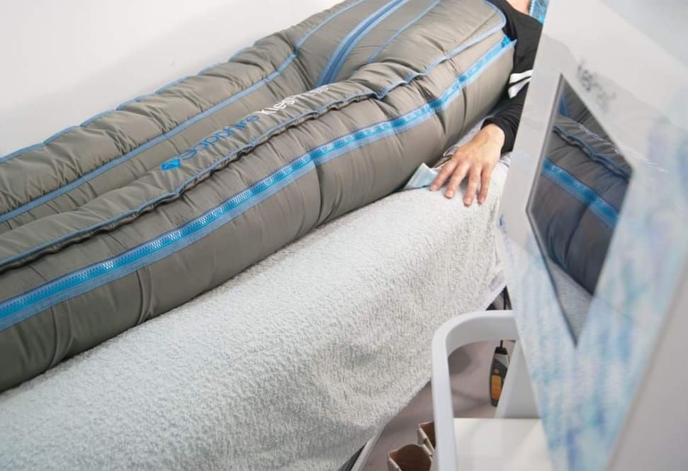 Persona recostada bajo una manta gris, con una mano visible junto a la pantalla del televisor.
