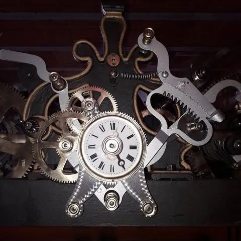 Un primer plano de un reloj con números romanos y engranajes.