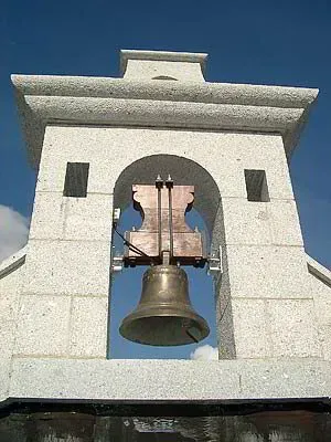 Una gran campana cuelga del costado de un edificio.