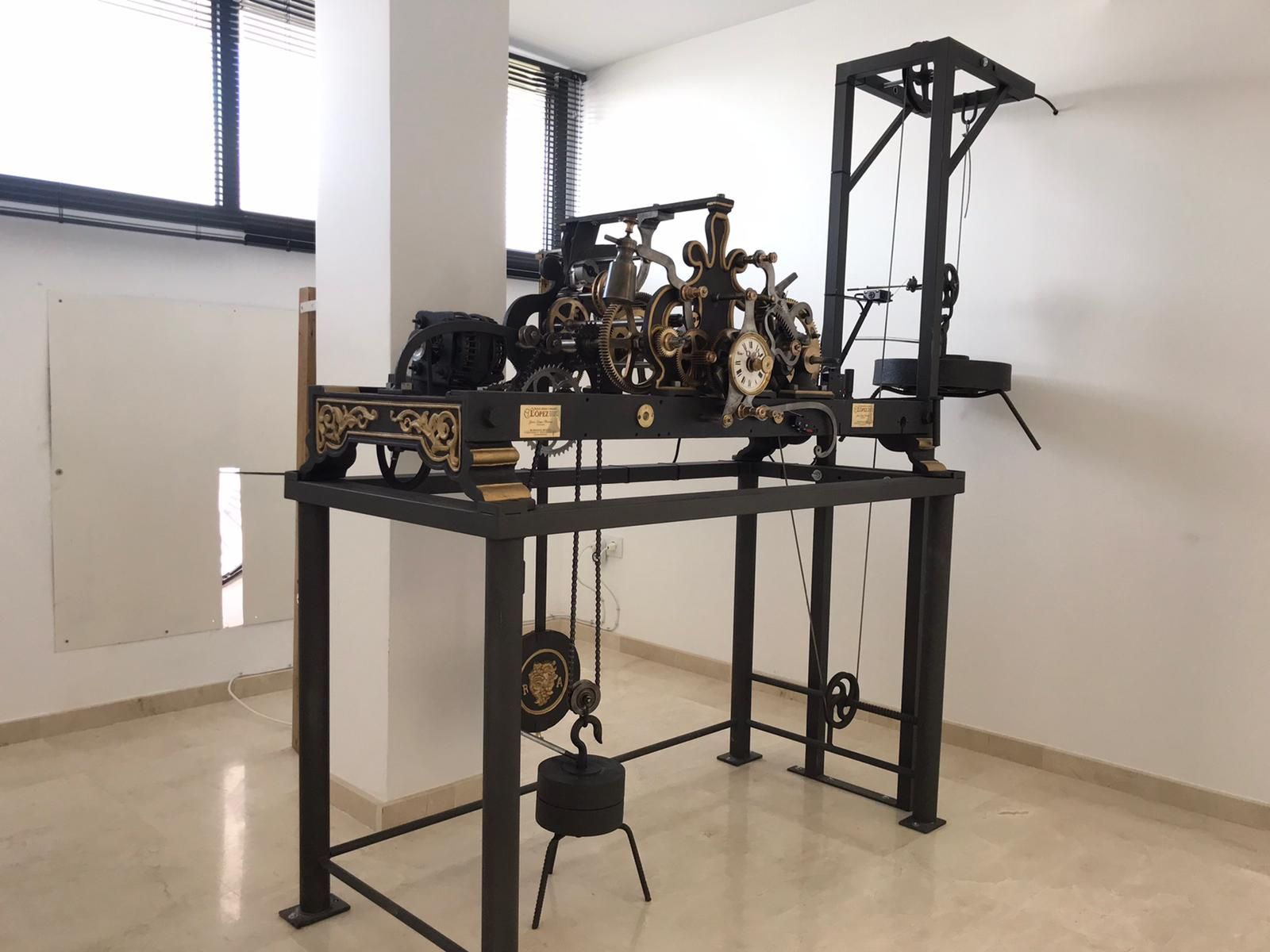 Un gran reloj está sentado sobre un soporte de metal en una habitación.