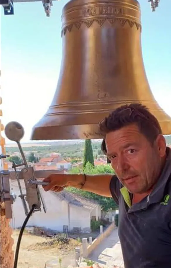 Un hombre señala una campana grande en una iglesia.