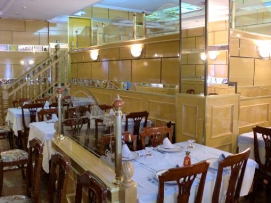 Interior del restaurante: paneles de madera, mesas dispuestas con manteles blancos, sillas.