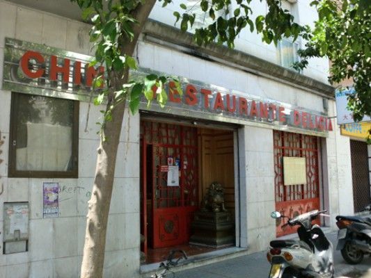 Restaurante chino con molduras y señalización en color rojo, scooter estacionada afuera.