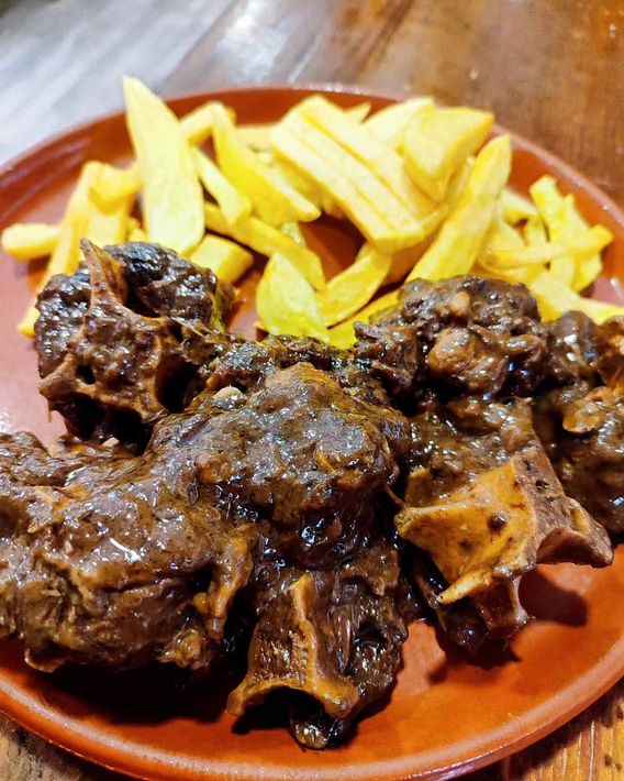 Un plato de carne y patatas fritas en una mesa de madera.