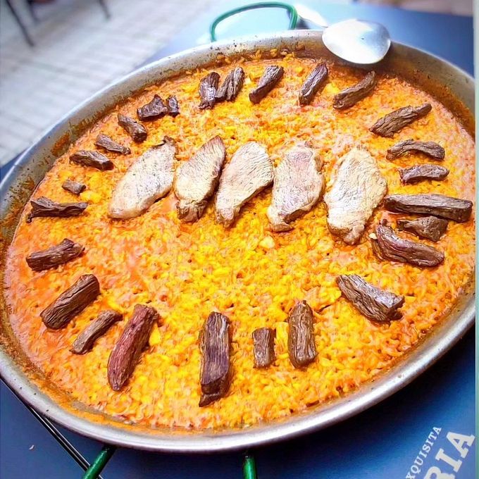 Una cacerola de comida con carne y arroz sobre una mesa con una cuchara.